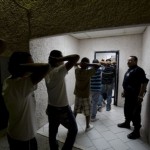 A municipal police officer, right, watches detainees brought in on drug possession charges enter the police station in Ciudad Juarez, Mexico. Local police have been given assault rifles and instructed not to patrol the streets alone, after receiving death threats from drug cartels over their own radio frequencies.